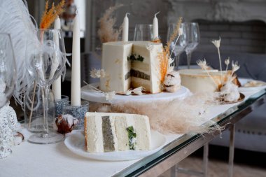 Kremalı ve kivili güzel bir düğün pastası, masa düzenleme ve tabakta bir dilim pasta..