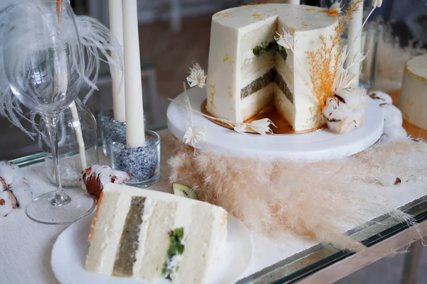 Belo bolo de casamento com creme e kiwi, mesa e um pedaço de bolo em um prato. — Fotografia de Stock