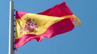 Rüzgarda dalgalanan İspanyol bayrağı. Mavi gökyüzüne karşı ulusal bayrak,
