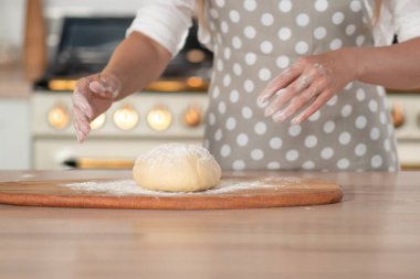Diz hamuru, el hamuru ve un yakın plan. Gri benekli önlüklü bir pasta şefi..