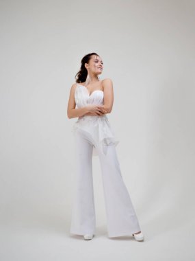 Şık ve zarif takım elbiseli esmer bir kadın. Pantolonlu bir gelinlik, modern tarzda..