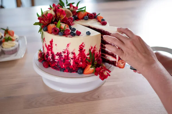 Μεγάλο όμορφο κόκκινο βελούδινο κέικ, με λουλούδια και μούρα στην κορυφή. Κόψτε μια μερίδα, — Φωτογραφία Αρχείου