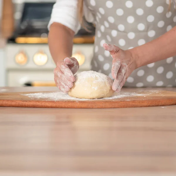 Amasse a massa de farinha, massa de mão e farinha close-up. Um chef de pastelaria em um avental de bolinhas cinza. — Fotografia de Stock