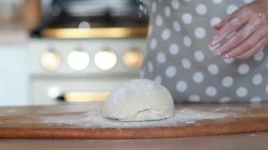 Diz hamuru, el hamuru ve un yakın plan. Gri benekli önlüklü bir pasta şefi..