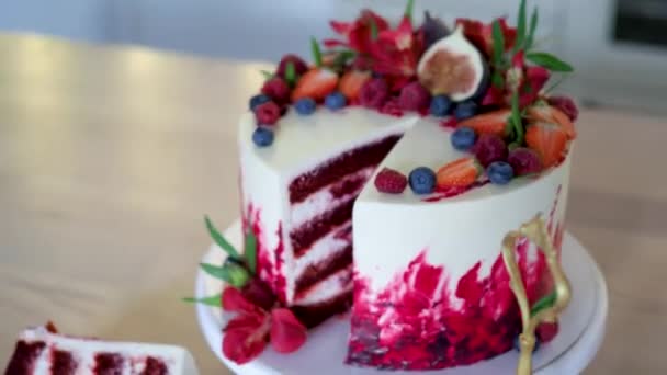 Grande bella torta di velluto rosso, con fiori e bacche in cima. Fetta su un piatto, dessert. — Video Stock