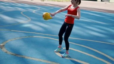 Genç bayan sporcu antrenman yapıyor, açık havada bir su ısıtıcısıyla antrenman yapıyor..