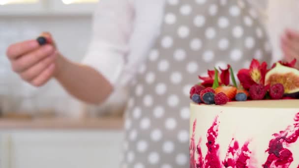 Kochen und Dekorieren von Kuchen mit Sahne. Junge Konditorin in der Küche dekoriert roten Samtkuchen — Stockvideo