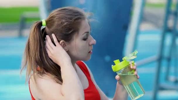 Genç bayan sporcu açık havada idmandan sonra su içiyor.. — Stok video