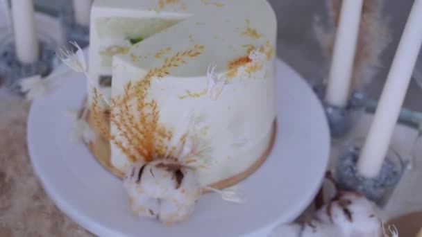 Prachtige bruidstaart met room en kiwi, tafel zetting en een stuk taart op een bord. — Stockvideo