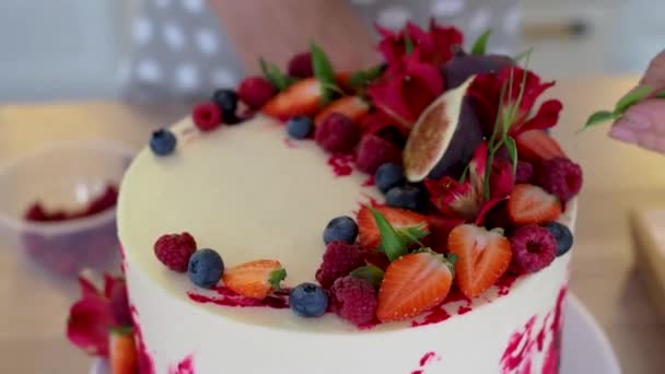 Kochen und Dekorieren von Kuchen mit Sahne. Junge Konditorin in der Küche dekoriert roten Samtkuchen — Stockvideo