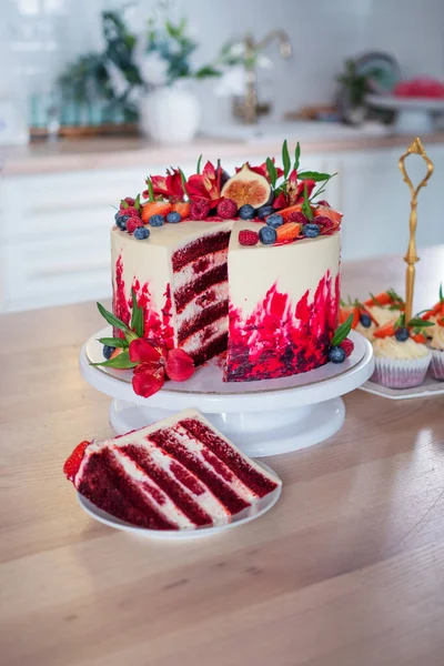 Big beautiful red velvet cake, with flowers and berries on top. Slice on a plate, dessert.