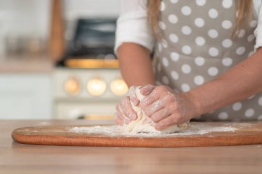 Diz hamuru, el hamuru ve un yakın plan. Gri benekli önlüklü bir pasta şefi..