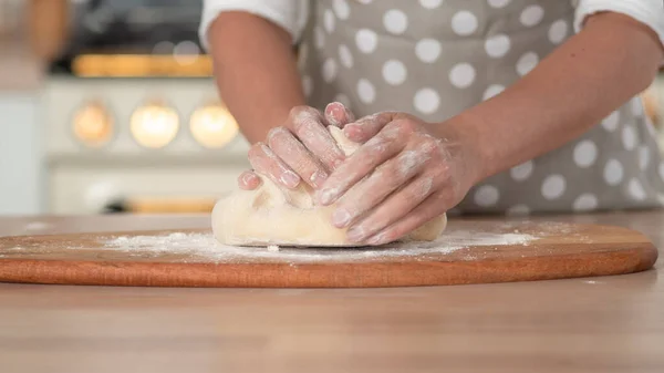 Amasse a massa de farinha, massa de mão e farinha close-up. Um chef de pastelaria em um avental de bolinhas cinza. — Fotografia de Stock