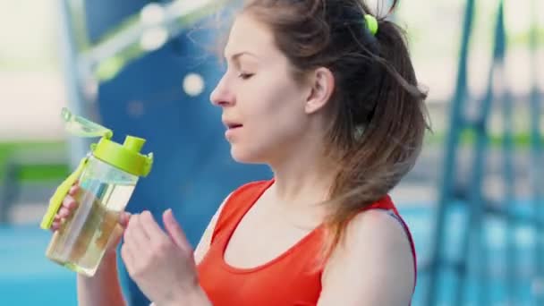 옥외에서 운동을 하다가 물을 마시는 젊은 여자 운동 선수. — 비디오