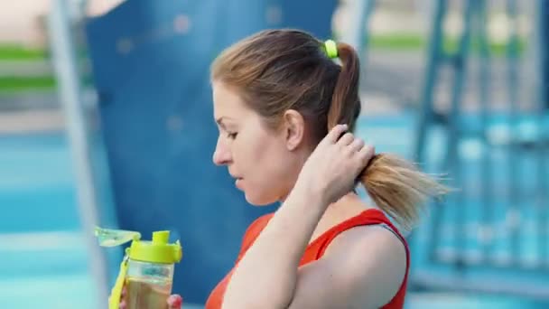 Mladá atletka pitné vody po cvičení na čerstvém vzduchu. — Stock video