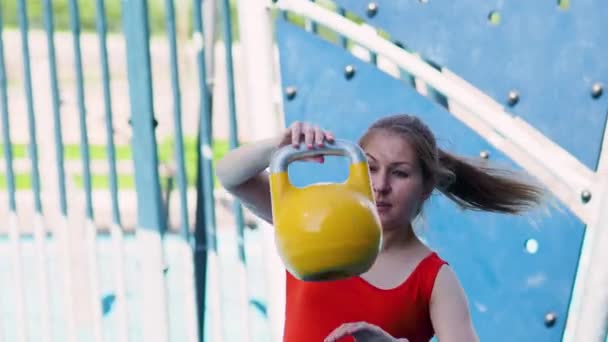 Gewichten jongleren. Jonge vrouwelijke atleet doen workout, training met een kettlebell in de open lucht. — Stockvideo