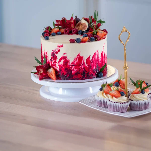 그 위에 꽃과 열매가 달린 크고 아름다운 붉은 벨벳케이크. 크림을 곁들인 달콤 한 머핀, — 스톡 사진