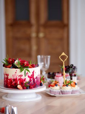 Üzerinde çiçekler ve böğürtlenler olan büyük güzel kırmızı kadife pasta. Kremalı lezzetli kekler.,