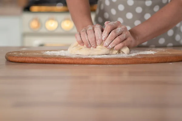 Amasse a massa de farinha, massa de mão e farinha close-up. Um chef de pastelaria em um avental de bolinhas cinza. — Fotografia de Stock