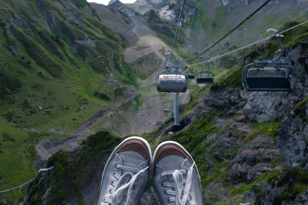 stock image Mountain resort in summer, sneakers on the background of a mountain landscape, first-person photo.