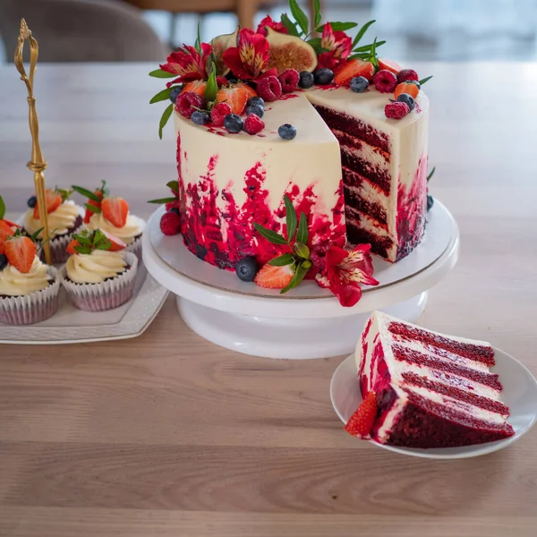 Grande bella torta di velluto rosso, con fiori e bacche in cima. Fetta su un piatto, dessert. — Foto Stock