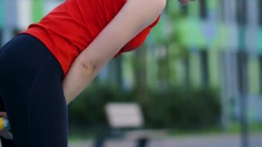 Genç bayan sporcu antrenman yapıyor, açık havada bir su ısıtıcısıyla antrenman yapıyor..