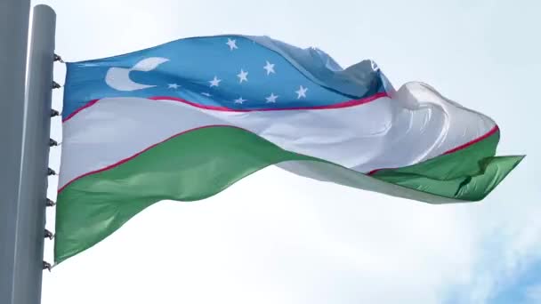 Uzbekistánská vlajka vlála ve větru. Národní vlajka proti modré obloze, — Stock video