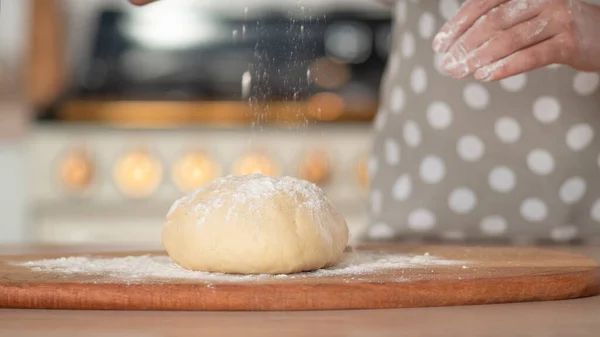 Amasse a massa de farinha, massa de mão e farinha close-up. Um chef de pastelaria em um avental de bolinhas cinza. — Fotografia de Stock