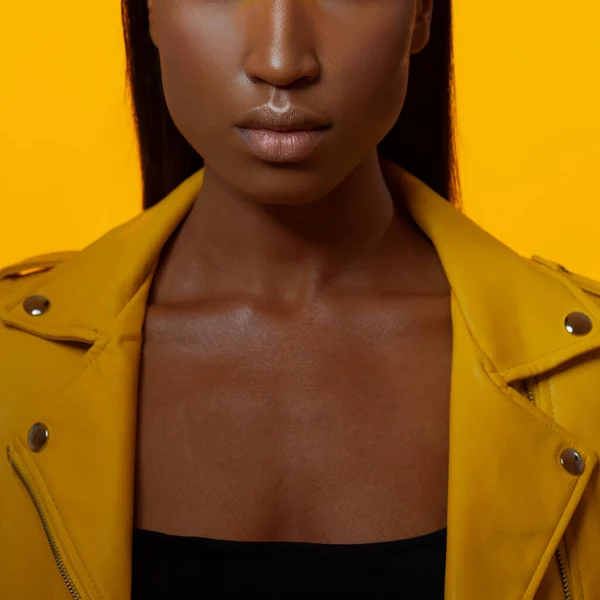 Bright stylish black woman on a yellow background in a yellow leather jacket, — Stock Photo, Image