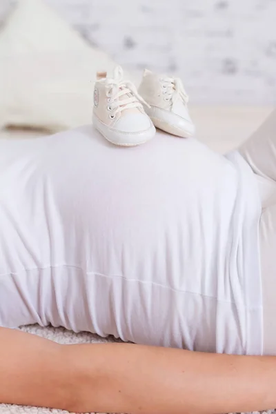 Schöne Schwangere Frau Mit Weißen Babyschuhen Auf Dem Bauch Hause — Stockfoto