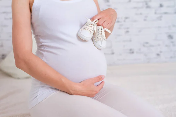 Hamile Kadının Karnında Odak Beyaz Bebek Patik Tutan Kadın — Stok fotoğraf