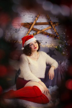 Noel ağacının önünde sandalyede oturan düşünceli kadın.