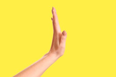 Dur işareti izole sarı arka plan üzerinde gösterilen El yakın çekim