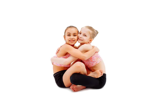 两个可爱的女孩体操运动员在美丽多彩的服装坐姿 — 图库照片