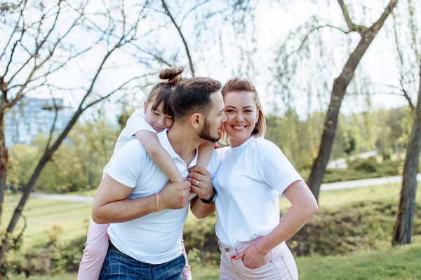 Jovem família feliz de três se divertindo juntos ao ar livre. Bonito. — Fotografia de Stock