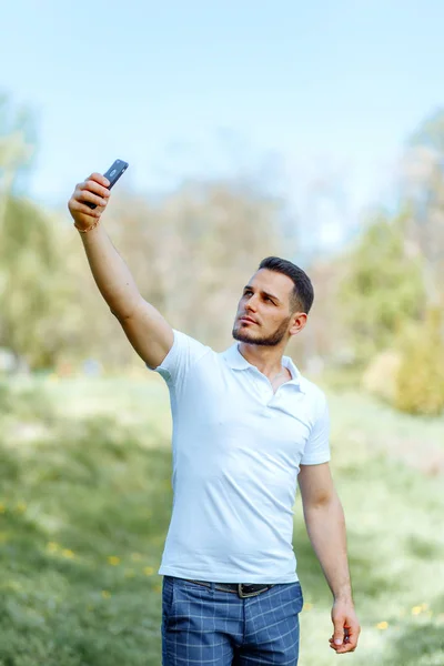 Cute guy takes a selfie on the phone in the sun. People, beautif — Stock Photo, Image