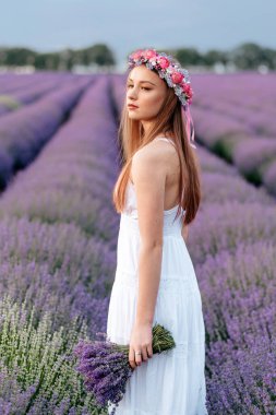Çiçekli lavanta tarlasında elinde buketle bekleyen hayalperest genç kadın, kapat.