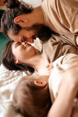 Aile huzurlu, anne ve baba yatakta uzanırken burunlarının tadını çıkarıyor.
