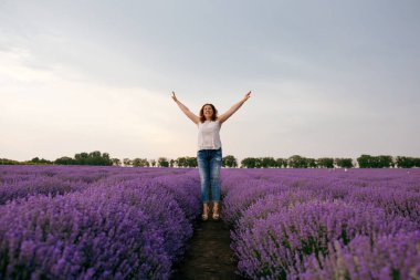 Mutlu ve neşeli kadın lavanta tarlasında mutluluğun tadını çıkarıyor.