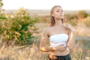 Güzel genç kadın günbatımının tadını çıkarıyor.