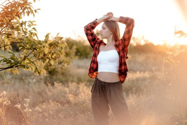 Güneşin batışında elleri kafasında güzel bir kadının portresi.