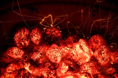 Alev ve kıvılcım geceleri ateş. Barbekü ızgara çukur parlayan ve yanan sıcak kömürü briket ile. Barbekü açık pişirme. 