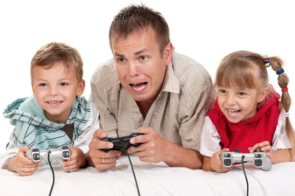 爸爸与女儿和儿子拿着操纵杆和玩视频游戏在控制台上在一起 幸福的家庭 父亲和小女孩和男孩有白色背景的有趣的游戏 带孩子玩耍的男人 — 图库照片