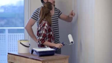 Yakışıklı baba kızını gösterilen nasıl boya duvarlar yapılır. Mutlu aile - adam ve Genç kız evde beraber onarım yapmak. Baba ve çocuk boyama bir rulo kullanarak duvar düz beyaz,.