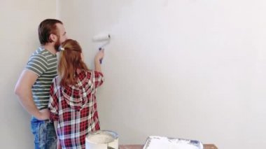 Yakışıklı baba kızını gösterilen nasıl boya duvarlar yapılır. Mutlu aile - adam ve Genç kız evde beraber onarım yapmak. Baba ve çocuk boyama bir rulo kullanarak duvar düz beyaz,.