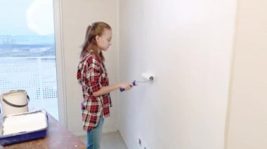 Teen kız boyama iç duvarlara boya silindiri kullanarak düz. Çocuk kendini onun odasına - aktif boya duvar beyaz boya ile onarım yapar. Ev yenileme veya tadilat kavramı.