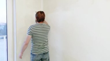 Sakallı adam boya iç boya silindiri kullanarak düz duvarlara. Onarım - aktif boya duvar beyaz boya ile yapıyor yakışıklı delikanlı. Ev yenileme veya tadilat kavramı.