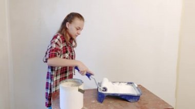 Teen kız boyama iç duvarlara boya silindiri kullanarak düz. Çocuk kendini onun odasına - aktif boya duvar beyaz boya ile onarım yapar. Ev yenileme veya tadilat kavramı.