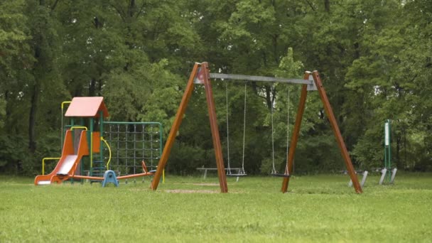Детская площадка с качелями после дождя — стоковое видео