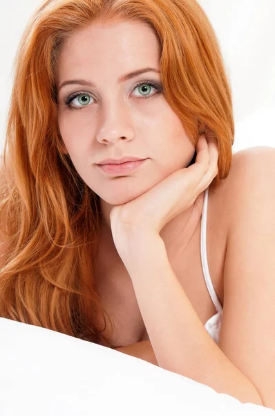 Ragazza con i capelli rossi su un letto — Foto Stock